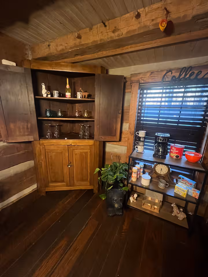 Coffee and refreshment area with wooden cabinets, glasses, coffee maker, cups, and supplies