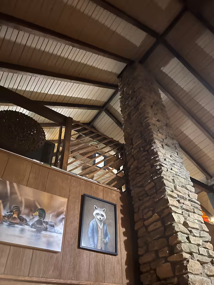 Rustic cottage loft with exposed beams, stonework, artwork, and cabin-style architectural details